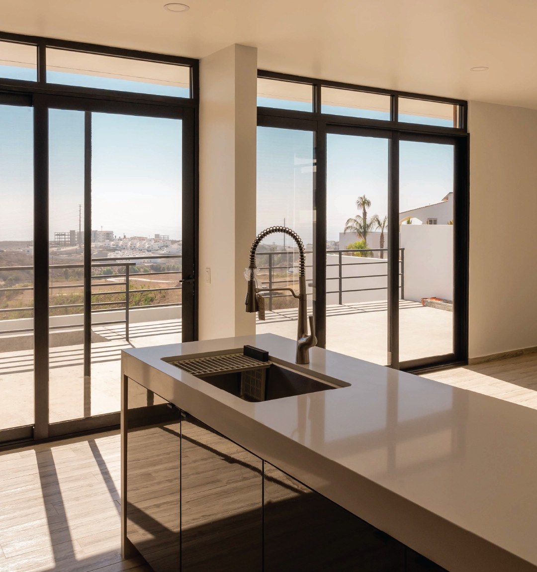Cocina con isla de cuarzo y ventanales hacia la terraza