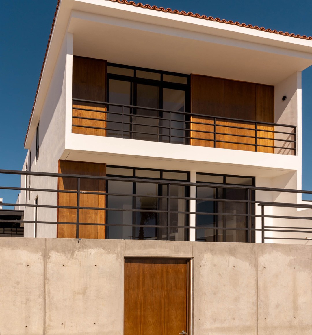 Fachada posterior de dos niveles con balcones y ventanales