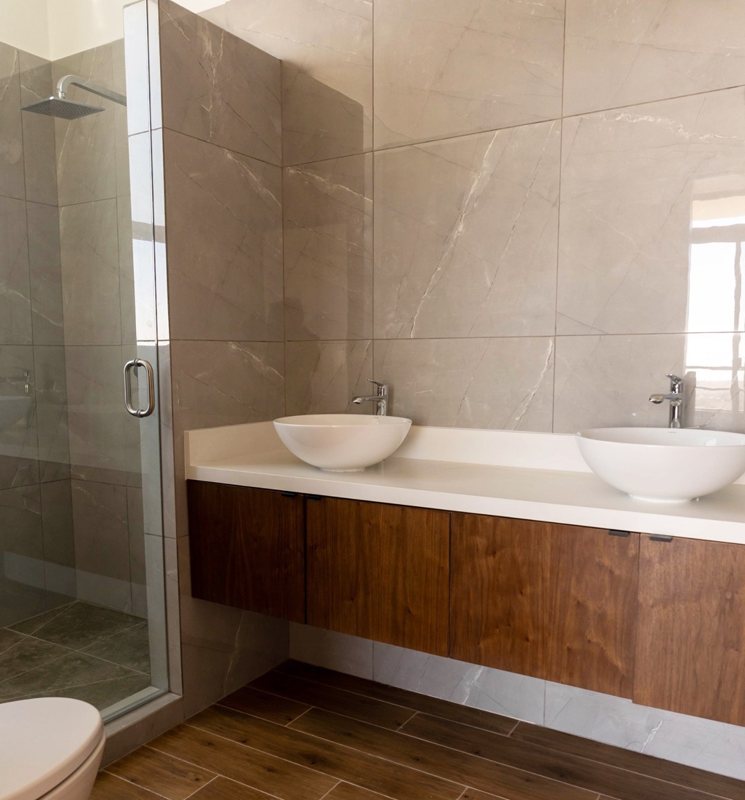 Baño con doble lavabo, mueble de madera y regadera de cristal